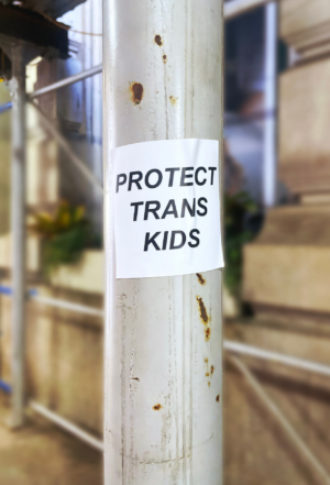 Photo of a scaffolding pole with a sticker that says "Protect Trans Kids"